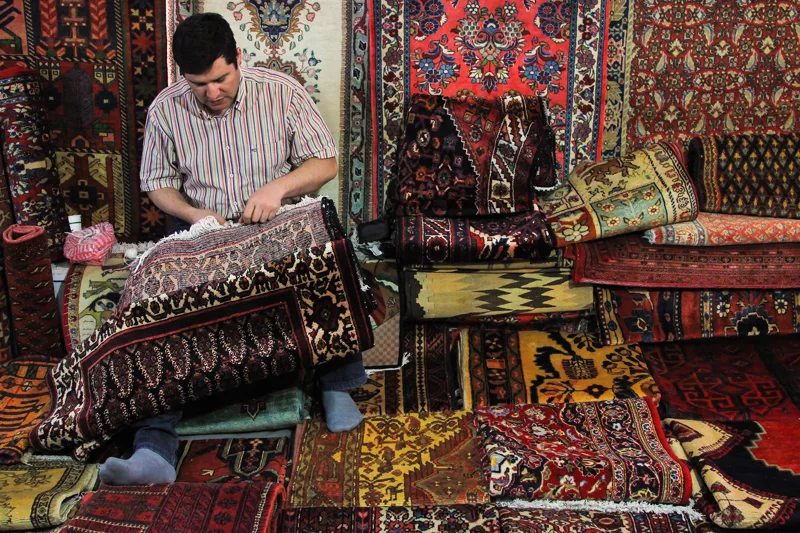 A craftsman at work surrounded by richly patterned textiles